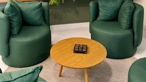 A modern living room with two green armchairs, a small wooden coffee table, and a staircase in the background. - Gran Amazon Av. Brasill (Belem)