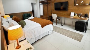 A modern hotel room with a bed, desk, chair, TV, and a small kitchenette. - Gran Amazon Av. Brasill (Belem)