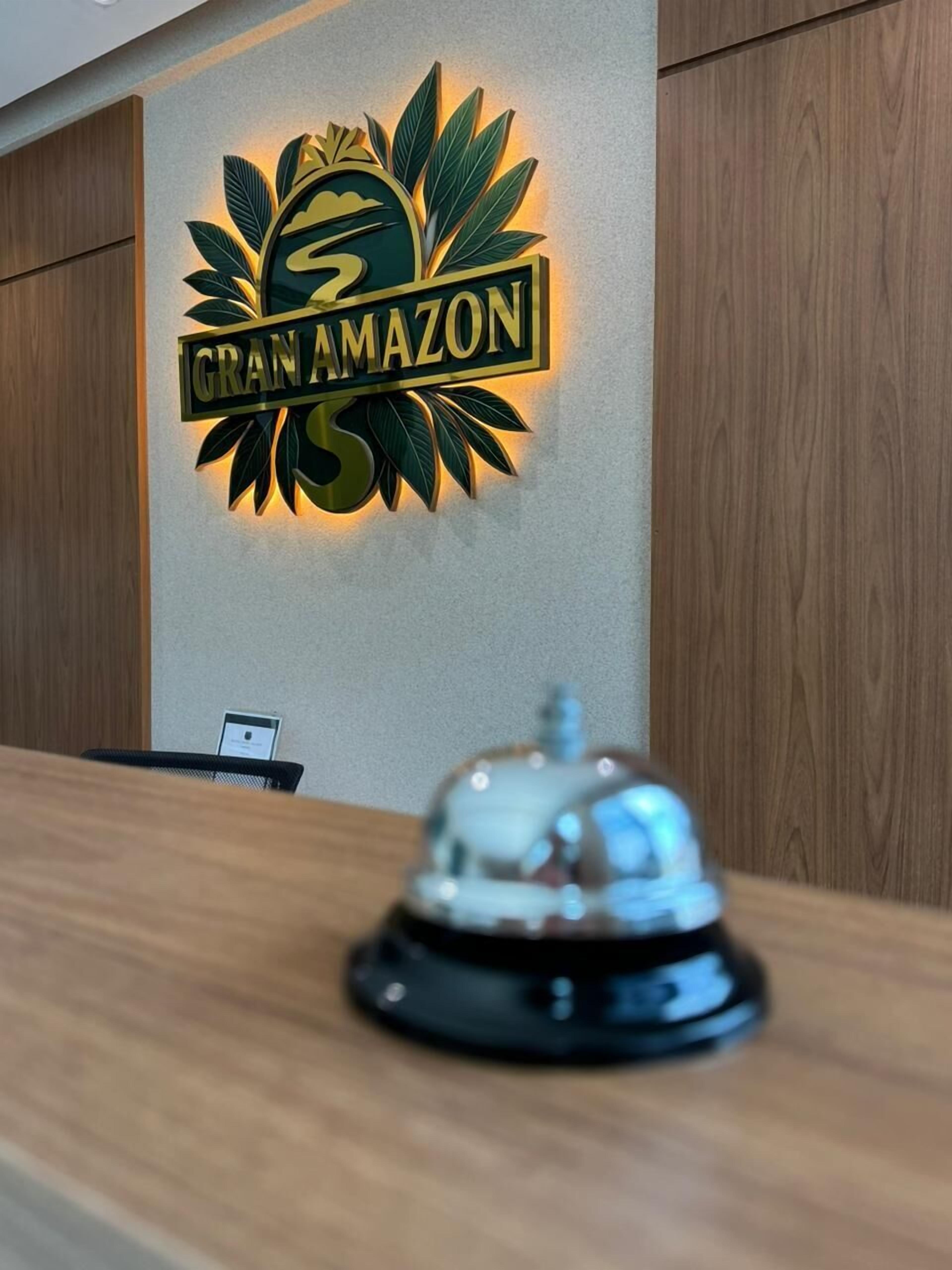 Un comptoir d’accueil avec le logo de « GRAN AMAZON » illuminé sur le mur.