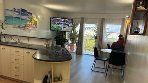 Una cocina moderna con una isla central, un comedor con mesa y sillas, y un ventanal con vistas al exterior.