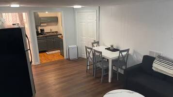 A compact living space with a dining area, a black sofa, and a small kitchen.