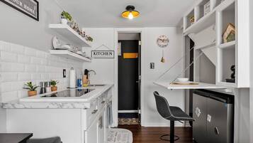 Een koelkast, een magnetron, kookgerei, borden en bestek, eettafels