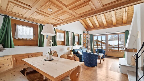 A spacious room with a wooden ceiling, a dining table with chairs, a sofa, and a blue armchair. - Luxury chalet St. Moritz with panoramic mountain view (Madulain)