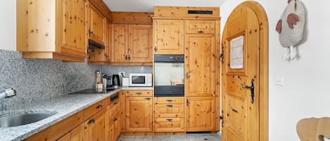 Eine Küche mit Holzausstattung, Granit-Arbeitsplatten, einer Mikrowelle und einem Herd.