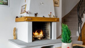 A fireplace with a mantel decorated with figurines and a small Christmas tree in a white room. - Luxury chalet St. Moritz with panoramic mountain view (Madulain)