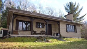 A two-story house with a covered porch, large windows, and a chimney. - cozy family house for rent on the ski mountain (Saint-Sauveur)