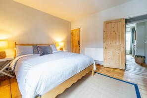 Ein Schlafzimmer mit einem Bett, Nachttischlampen, einem Holzschrank und einer Heizung.