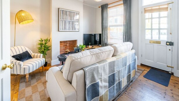 A cozy living room with a sofa, a television, a fireplace, and a door with a window. - Swift Host |Off Unthank Road | 2 bed + Parking + Garden (Norwich)