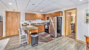 A modern kitchen with wooden cabinets, stainless steel appliances, and a central island.