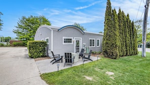 A single-story mobile home with a curved roof, a front porch with outdoor seating, and a well-maintained lawn.