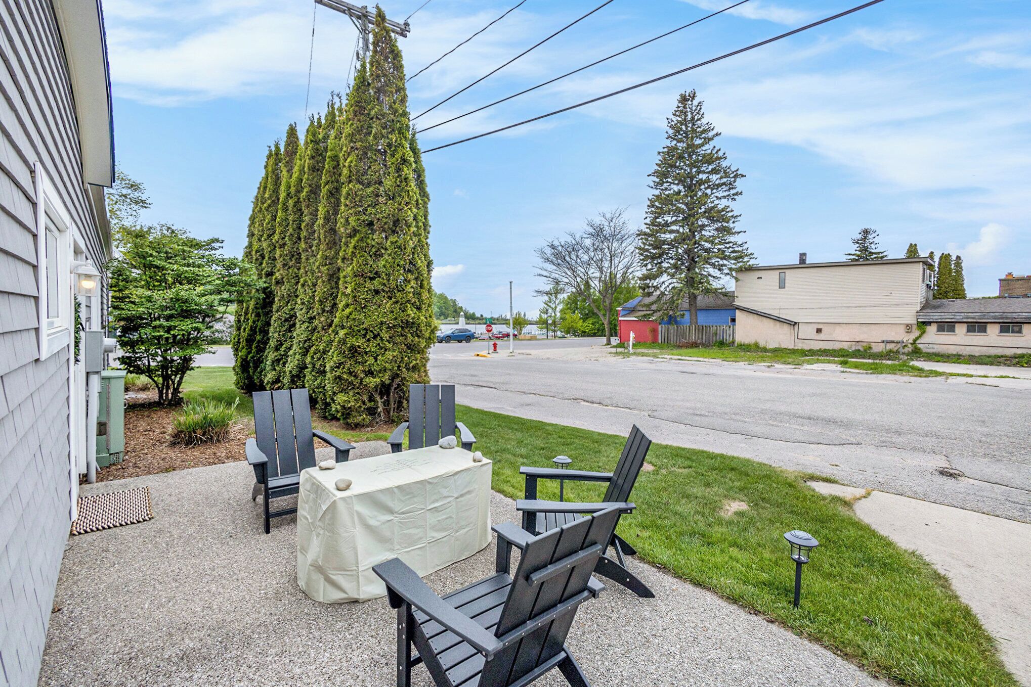 A patio with outdoor seating, a tall coniferous tree, and a street view in the background.