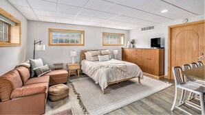 A bedroom with a bed, a sofa, a desk, and a TV.