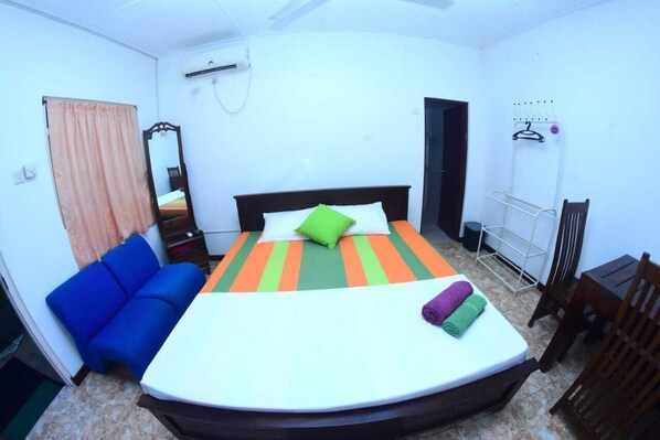 A bedroom with a bed, a blue sofa, a mirror, and a drying rack. - Kithula (Talpe)
