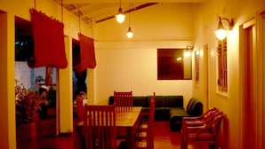 A dining area with wooden furniture, a sofa, and hanging red fabric decorations. - Kithula (Talpe)