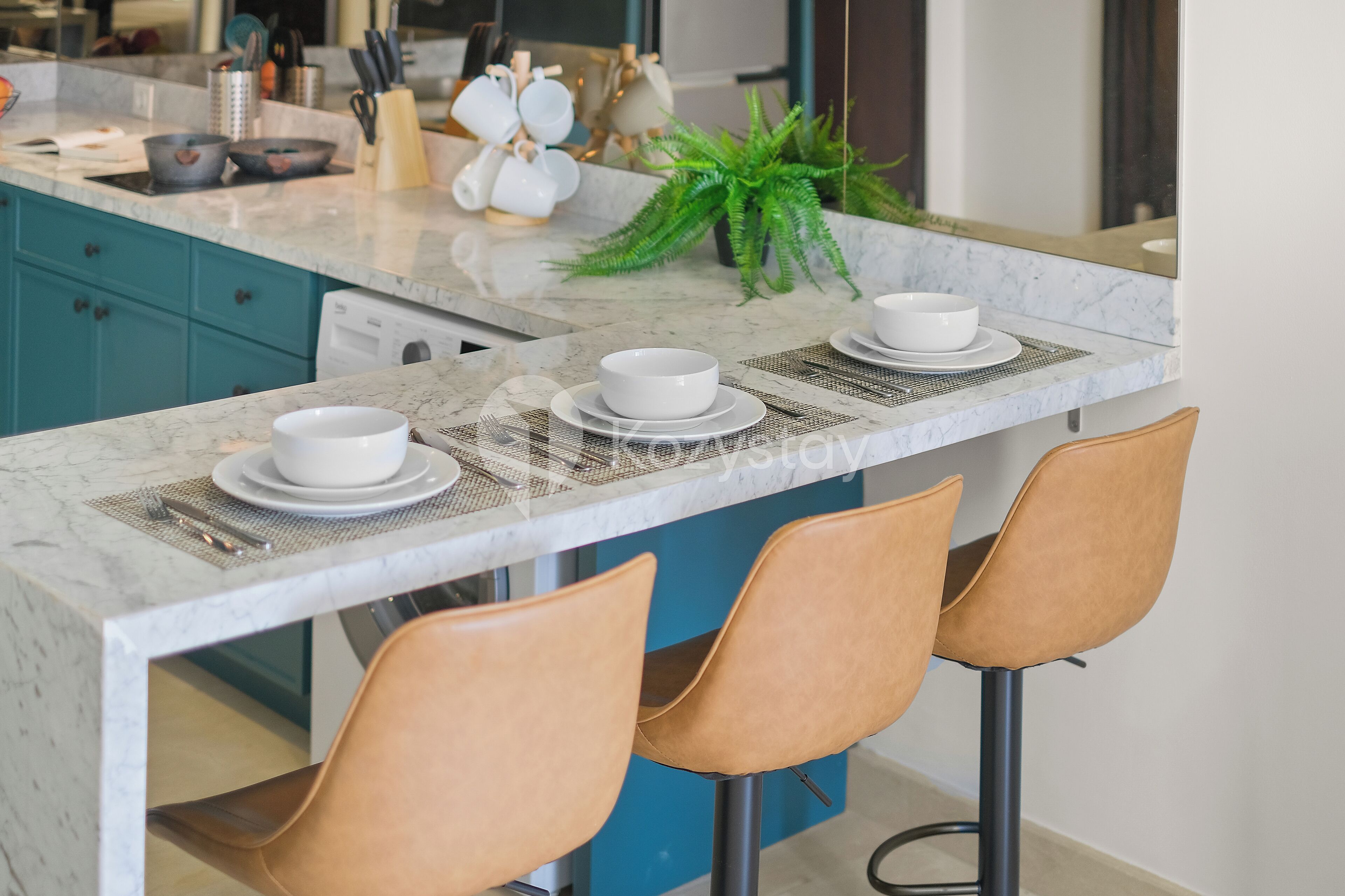 A kitchen island with a marble countertop, three stools, and a potted plant.
