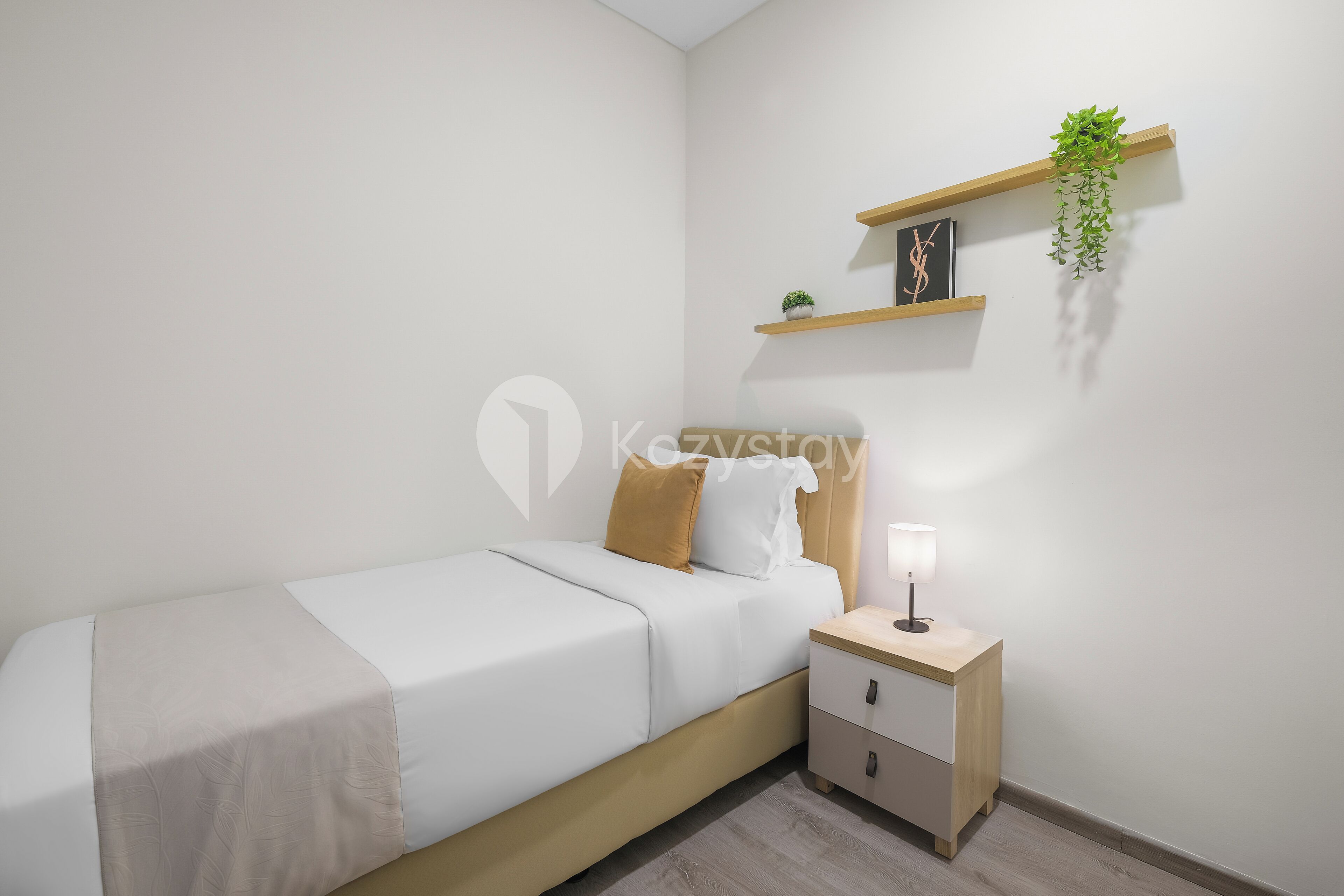 A minimalist bedroom with a bed, bedside table, and a wall-mounted shelf with a plant.