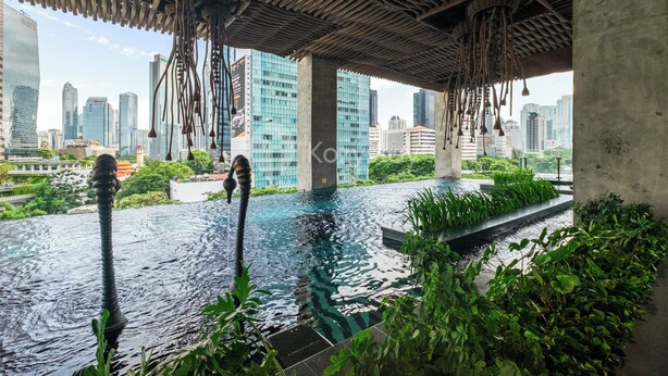 Une piscine sur le toit, agrémentée de sculptures suspendues, entourée de verdure et offrant une vue panoramique sur la ville.