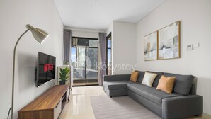 Un salon moderne avec un canapé gris, un meuble TV en bois et un lampadaire.