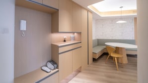 Eine moderne Küche mit integrierten Schränken, einem fest eingebauten Telefon und einer kleinen Arbeitsplatte. Im Essbereich steht eine Holzbank und ein runder Tisch mit einem Stuhl.