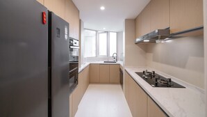 Eine moderne Küche mit einem Edelstahl-Kühlschrank, einem Einbauofen, einer Spülmaschine und einem Gasherd.