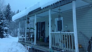 Ein mit Schnee bedecktes Haus mit Veranda, Fenster und Tür.