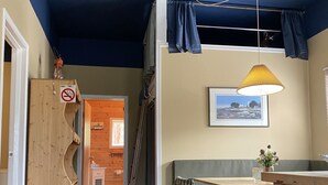 Ein gemütliches Zimmer mit Holzboden, einer karierten Bank, einem Tisch und einer Hängelampe.