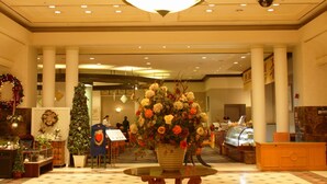 A lobby with a large chandelier, a Christmas tree, and a floral arrangement. - Legend Hotel (Daejeon)