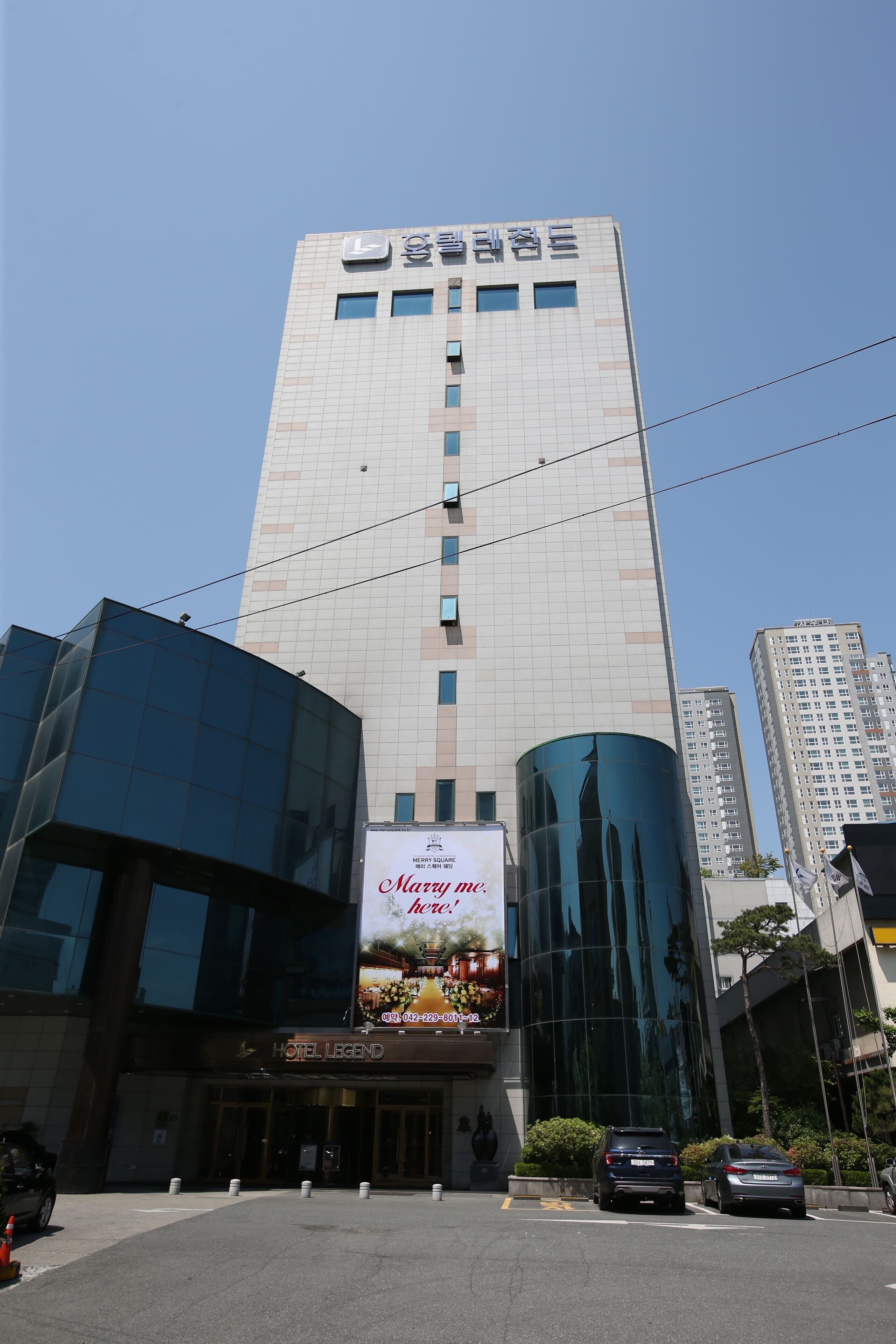 A hotel with a modern glass facade, a prominent sign, and a clear sky.