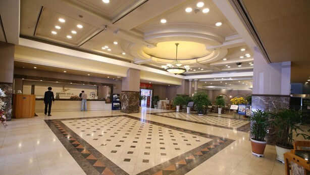 A spacious lobby with a large tiled area, a reception desk, and potted plants. - Legend Hotel (Daejeon)