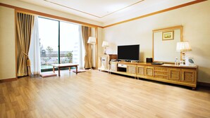 A spacious hotel room with a large sliding glass door leading to a balcony, a wooden TV stand with a flat-screen TV, and a large mirror. - Legend Hotel (Daejeon)