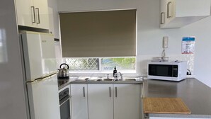 A modern kitchen with white cabinets, a refrigerator, an oven, a microwave, and a sink. - U07 Tripcony 2 Bedroom w Balcony (Sunshine Coast)