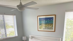 A neatly made bed with white and pink bedding, a ceiling fan, and a framed artwork on the wall. - U07 Tripcony 2 Bedroom w Balcony (Sunshine Coast)