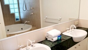 Une salle de bain avec deux lavabos, une baignoire et une douche.
