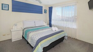 A bedroom with a bed, a nightstand, a ceiling fan, and a window with curtains.