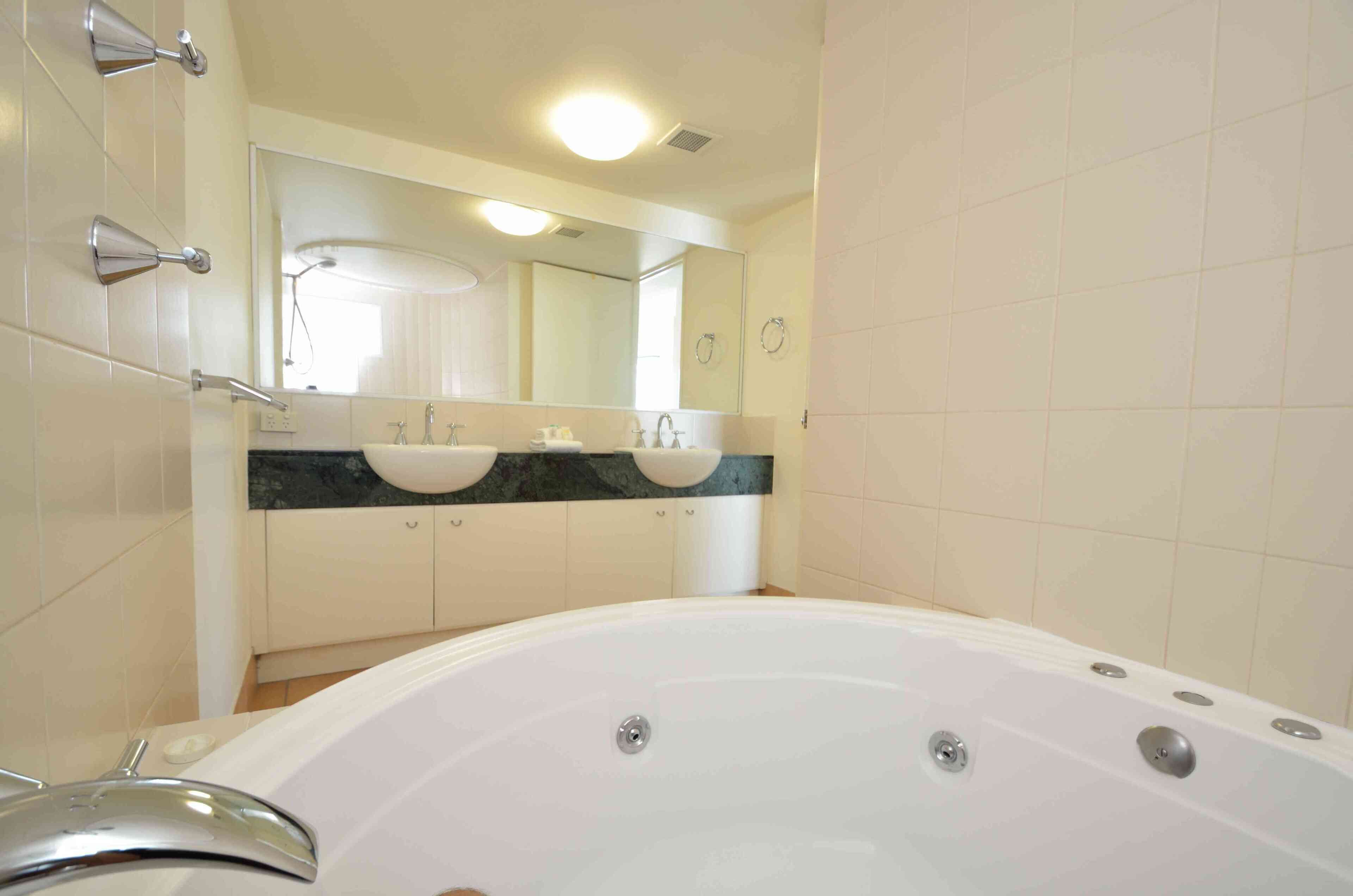Un bagno con una grande vasca, due lavandini e uno specchio sopra i lavandini.