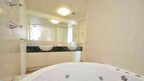 A bathroom with a large bathtub, two sinks, and a mirror above the sinks.