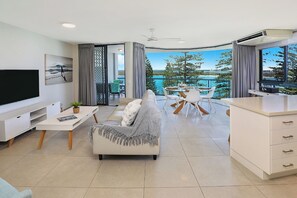 A modern living room with a sofa, TV, and dining area.