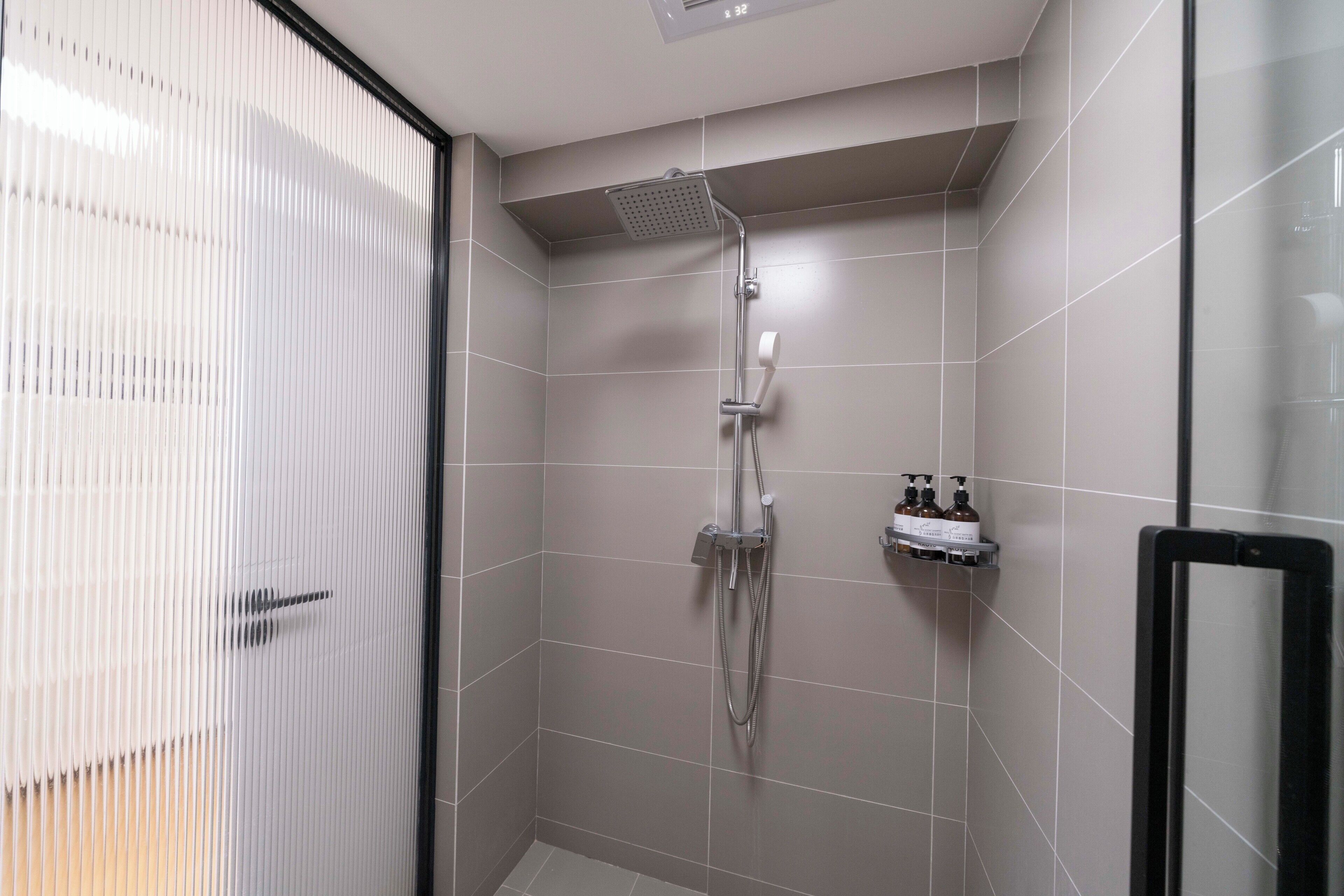 A modern shower area with a handheld showerhead, a wall-mounted faucet, and a glass door.