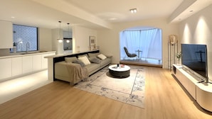 Un saló modern amb un sofà, una taula de centre i una televisió. Hi ha una zona de cuina amb un rentaplat i armaris.