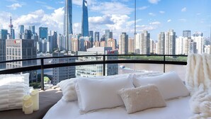 A hotel room with a large window offering a city skyline view.