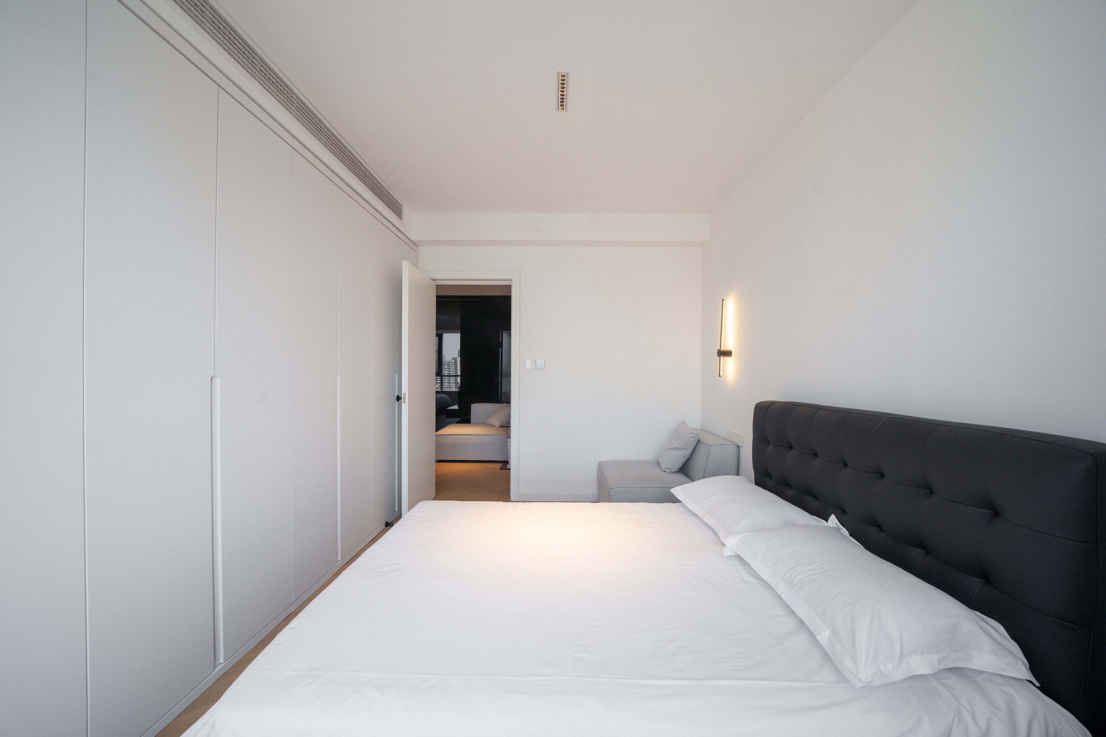 A bedroom with a bed, a wardrobe, and a sofa.