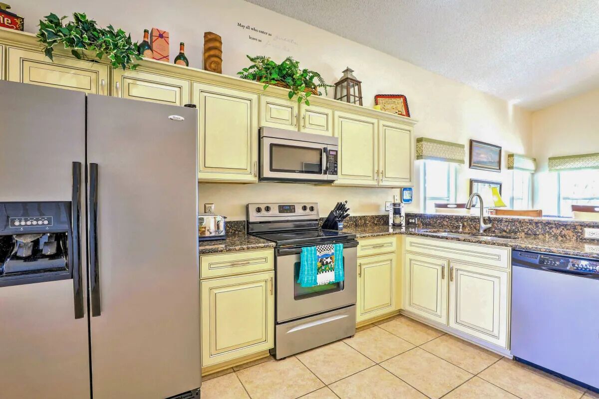 A kitchen with light-colored cabinets, a stainless steel refrigerator, a microwave, an oven, and a dishwasher.