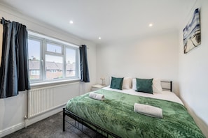 Ein Schlafzimmer mit Bett, Fenster, Heizkörper und einem Gemälde an der Wand.