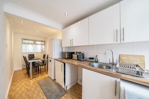 A modern kitchen with white cabinets, a wooden countertop, and stainless steel appliances.
