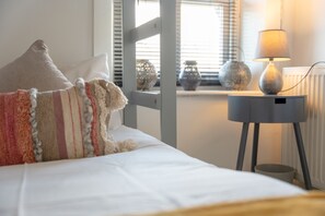 A neatly made bed with pillows, a bedside lamp, and decorative vases on a windowsill. - Cosy Cottage - Sleeps 6, Parking & Pet Friendly! (Nelson)