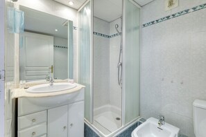 Un baño con lavamanos, espejo, ducha e inodoro.