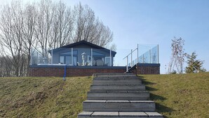 Un bâtiment moderne doté d’une façade en verre, d’une base en briques et d’un escalier en pierre menant à une rambarde en verre.