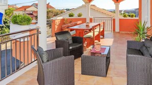 Une terrasse extérieure aménagée avec des meubles en osier, une table et des chaises.