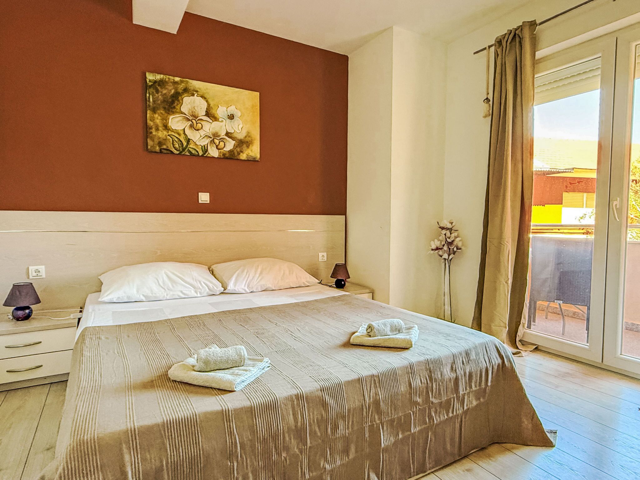 A bedroom with a large bed, a nightstand, a lamp, and a painting on the wall.