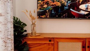 A room with a cityscape painting, a wooden cabinet, a potted plant, and a bench.